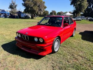 Classic red BMW E30 on display at the SoCal Vintage BMW Show in Southern California, captured by US Auto Collisions of Burbank, CA.